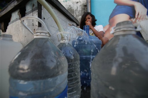 In this March 12, 2013 photo, a Filipino girl watches at a makeshift water station in suburban Pasay, south of Manila, Philippines. Ninety-one percent of people living in Asia have improved access to clean water, a remarkable achievement over the last two decades in the world's most populous region. But its richest countries and wealthiest citizens likely have better water supplies and governments better prepared for natural disasters. - (AP Photo/Aaron Favila)